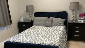 Une chambre bien rangée, avec un lit, deux tables de chevet et une fenêtre avec des rideaux.