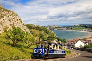 Eine Küstenstraßenbahn mit Fahrgästen, die an der Küste entlangfährt, mit Blick auf Klippen und Meer.