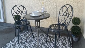 Une petite table ronde, deux chaises, une bouteille de spiritueux et un verre posés sur la table.