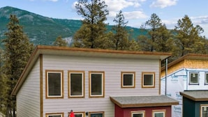 A two-story building with a balcony, a garage, and a view of mountains. - Hideaways| Mins to Lake| King Bed |Dbl Garage| AC (Invermere)