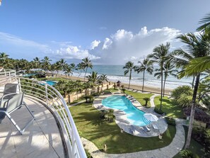 Un resort con piscina, sillas de descanso y vistas a la playa y al océano.