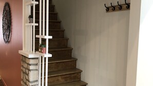 Eine Treppe mit Holzstufen und weißen Geländern, die zu einem Podest mit einem an der Wand befestigten Kleiderhaken führt.