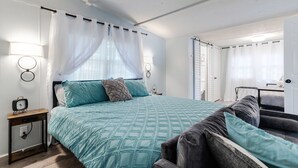 Ein Schlafzimmer mit Bett, Nachttischen, einer Lampe und einem Fenster mit Vorhängen.