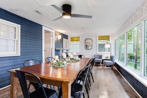 Un coin repas avec une table en bois, des chaises noires et un ventilateur de plafond.
