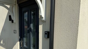 Eine dunkle Haustür mit Fensterteil, einem Briefkasten und der Hausnummer 123 an der Wand.