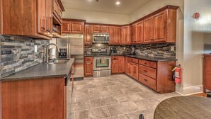 A kitchen with wooden cabinets, a granite countertop, a stainless steel refrigerator, a microwave, an oven, and a stone backsplash. - Perch 3 - Luxury Condo | Downtown Location | Modern and Contemporary (Blue Ridge)