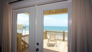 A sliding glass door leading to a wooden deck with a view of the ocean. - Toes in the Sand - Gulf Beachside, 4 Bedroom, 4 Bath, Dog Friendly, Sleeps 12 (Dauphin Island)