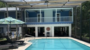 Un área de piscina con terraza cubierta, sillas de descanso y ventilador de techo.