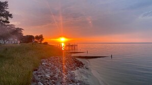A sunset over a calm body of water with a pier extending into the water.