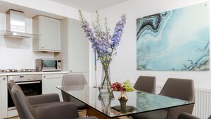A modern kitchen with white cabinets, a microwave, and a gas stove. - Refurbished! OXFORD STREET PHENOMENAL XXL DESIGN HOUSE IDEAL FOR GROUPS (London)