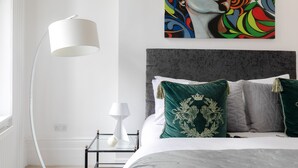 A modern bedroom with a bed, a nightstand, a lamp, and a colorful painting on the wall. - Refurbished! OXFORD STREET PHENOMENAL XXL DESIGN HOUSE IDEAL FOR GROUPS (London)