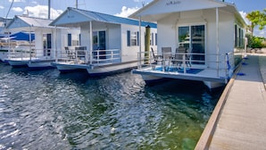 Una casa sull'acqua galleggiante con terrazza coperta e area relax, ormeggiata in una marina.