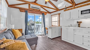 Un'ampia zona giorno con un divano modulare grigio, travi in legno e una ventola a soffitto.