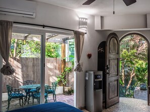 A room with a sliding glass door leading to a patio, a refrigerator, a table with chairs, and a decorative heart on the wall. - Casa Zen overlooking the Bay (Sayulita)