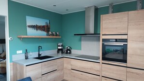 Una cucina moderna con pareti verde acqua, mobili in legno, forno a incasso e una macchina per il caffè.