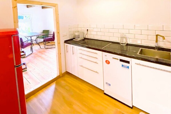 Una cocina compacta con armarios blancos, encimera negra y pileta de acero inoxidable.