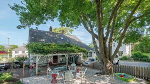 Un espacio de estar al aire libre cubierto con una pérgola, un árbol y una piscina pequeña.