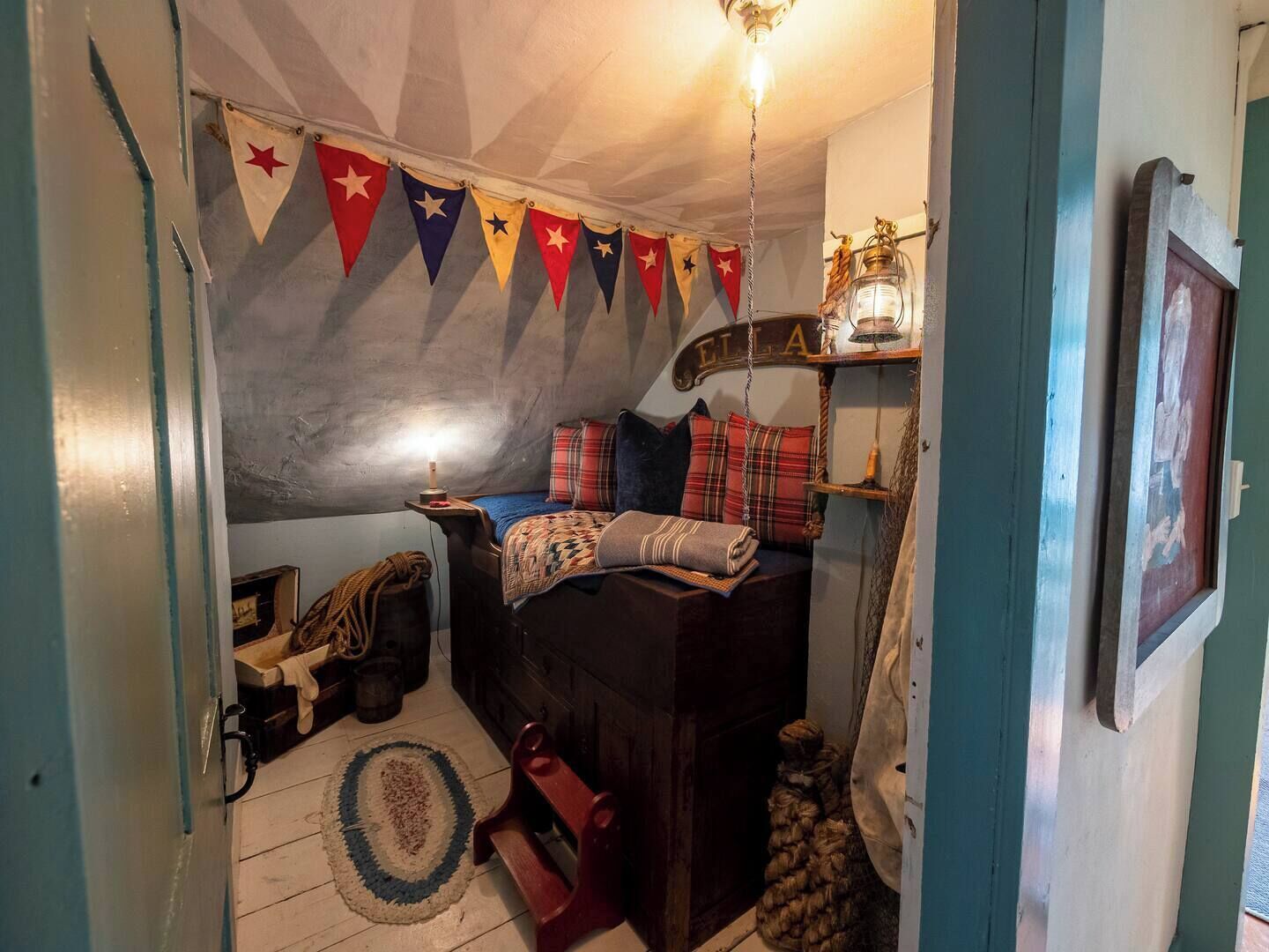 A cozy room with a bed, a hanging light fixture, and a shelf with a lantern.