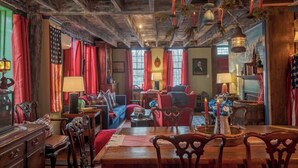 Una habitación tradicional con techo de madera, cortinas rojas, una mesa de comedor y un sofá azul.