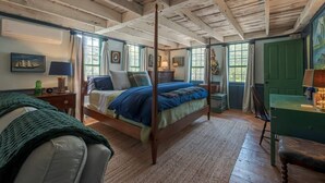 Una habitación tradicional con una cama con dosel, una puerta verde y un techo de madera.