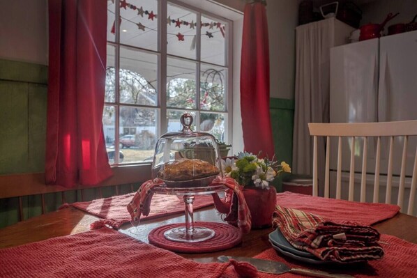 Une table à manger avec un panier à pain, un cloche de verre et un vase de fleurs.