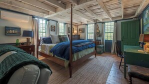 A traditional room with a four-poster bed, wooden beams on the ceiling, and a green door. - Historic 1807 Williams Home... A Nautical New England Inspiration!  (Old Mystic)
