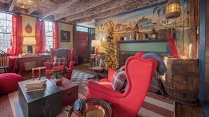 A cozy room with a wooden ceiling, a fireplace, a Christmas tree, and a mural on the wall. - Historic 1807 Williams Home... A Nautical New England Inspiration!  (Old Mystic)