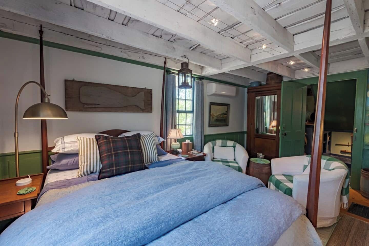 Un dormitorio con una cama grande, una mesita de noche, una lámpara, una silla y un espejo.