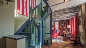 A staircase with green railings leading to a dining area with a red chair and wooden table. - Historic 1807 Williams Home... A Nautical New England Inspiration!  (Old Mystic)