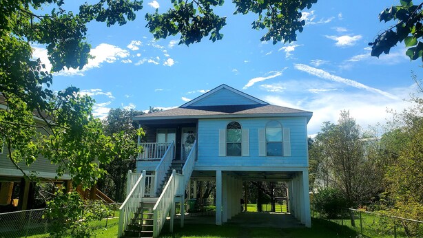 A two-story house with a covered porch and a staircase leading to the upper level. - Peggy  Sue (Pass Christian)