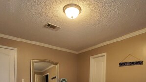 A bedroom with a bed, dresser, mirror, and a sign on the wall. - Peggy  Sue (Pass Christian)