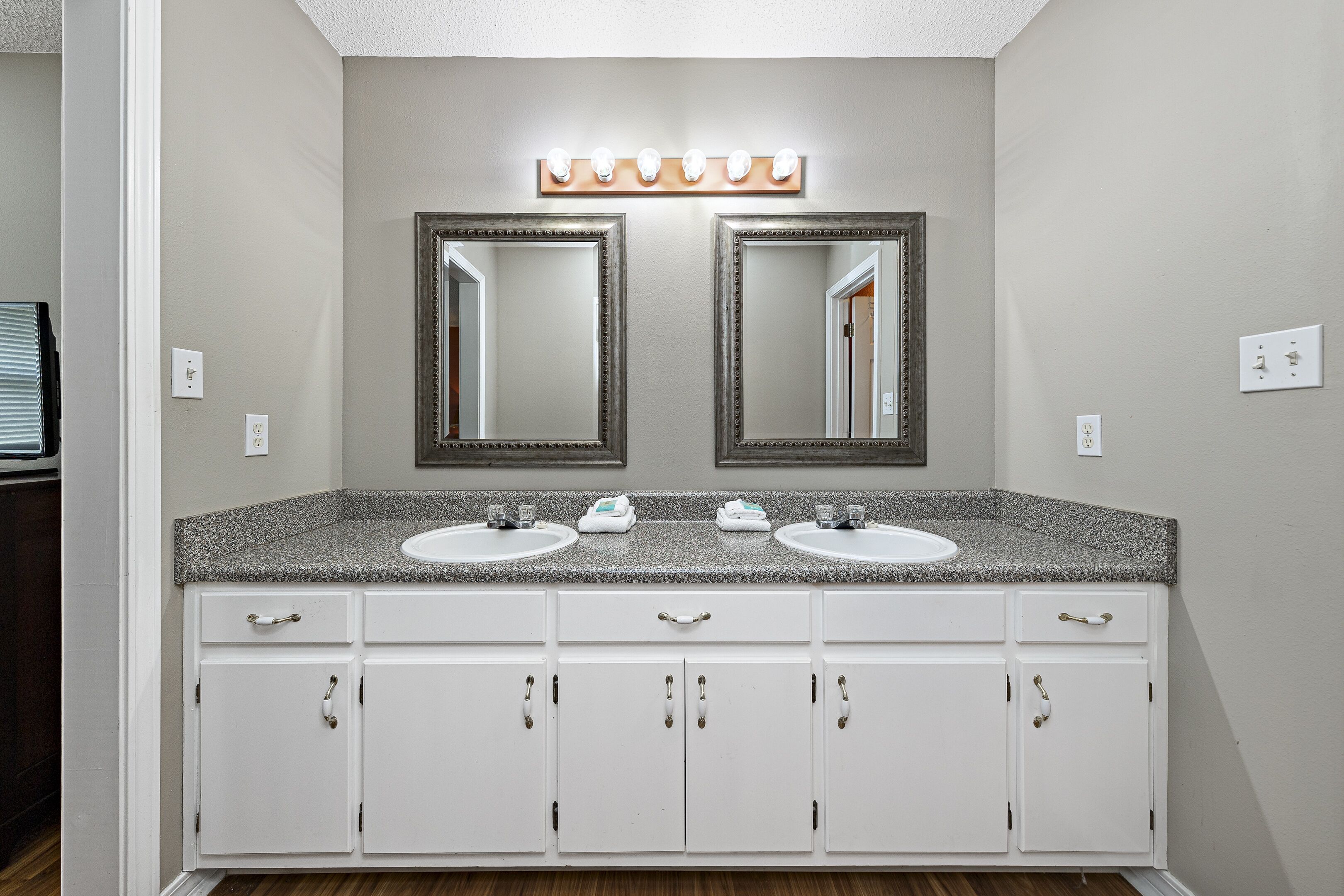 Une salle de bain avec deux lavabos, un meuble-lavabo avec des tiroirs et un miroir au-dessus des lavabos.