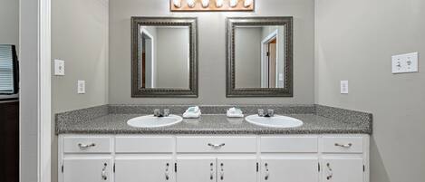 Une salle de bain avec deux lavabos, un meuble-lavabo avec des tiroirs et un miroir au-dessus des lavabos.