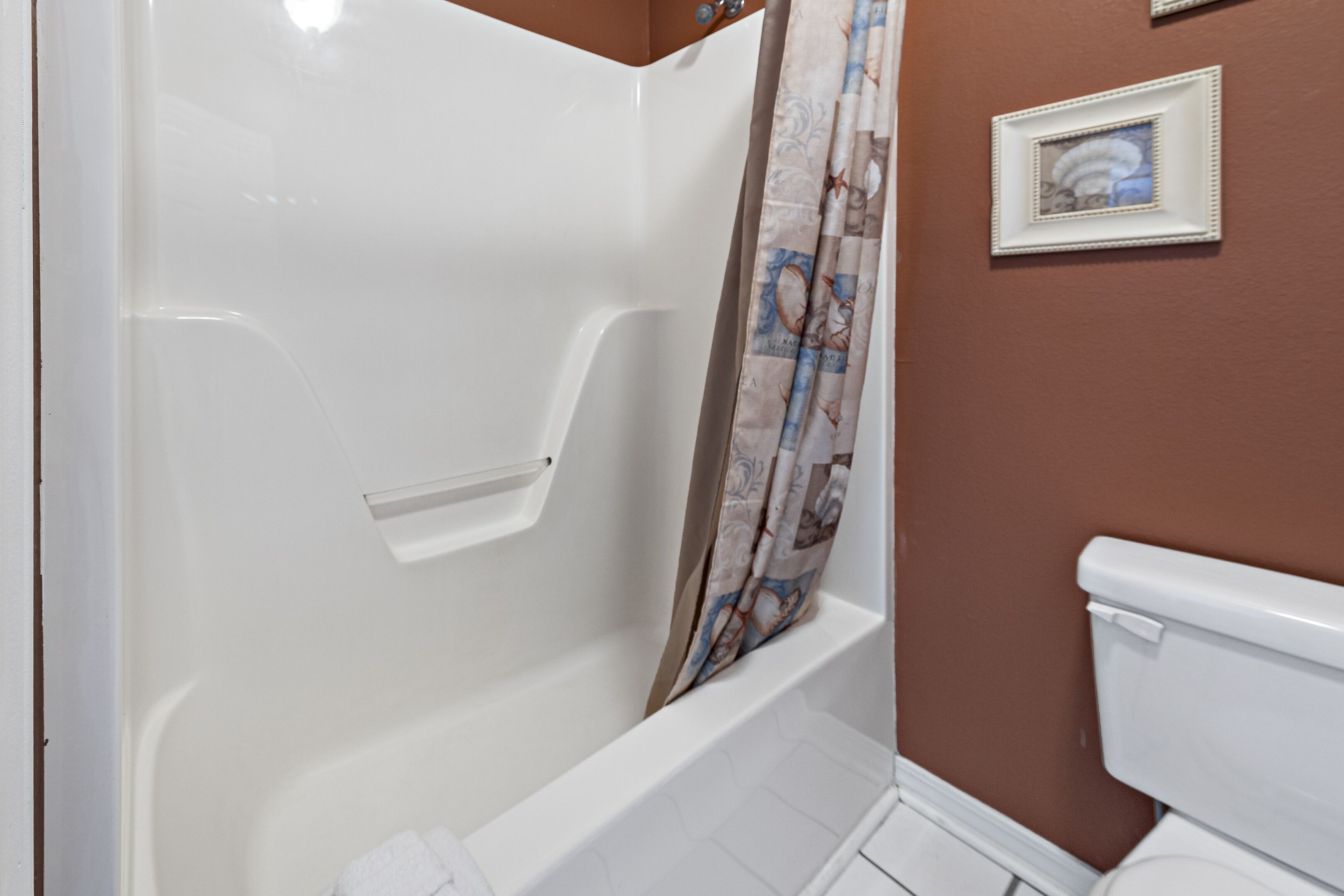 Een badkamer met douche, toilet en een inlijsting foto aan de muur.
