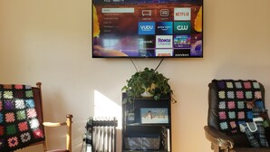 Una sala de estar con un televisor de pantalla plana montado en la pared mostrando la interfaz de un servicio de transmisión.
