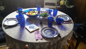 Una mesa redonda para comer con cristalería azul, platos y un bol de ensalada.