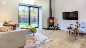 Una sala de estar moderna con chimenea, un sofá, una mesa de centro y un televisor montado en la pared.