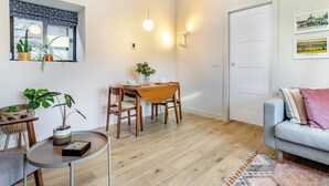 Una sala acogedora con comedor, un sofá y una mesita con una planta.