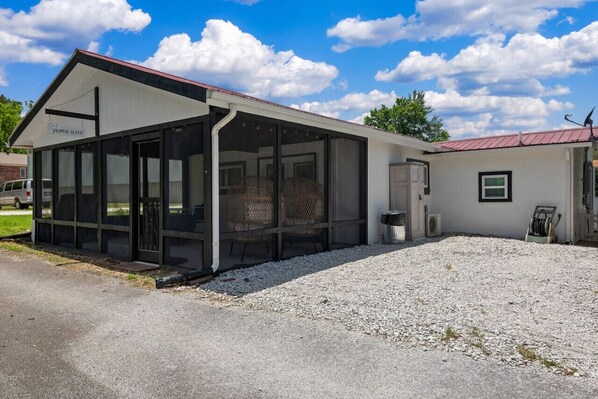 Een gebouw met een overdekt terras, een bord met de tekst 'Jasper Suite' en een grindpad.