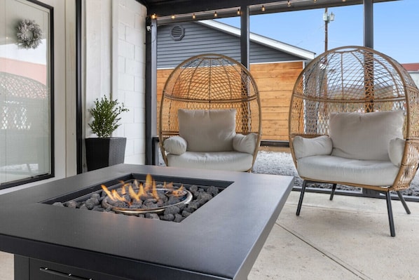 A modern outdoor seating area with a fire feature, wicker chairs, and a potted plant. - Sweet Jasper Suite-Summer Vacation W/ Hot Tub (Jasper)