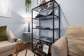 Ein Wohnzimmer mit einer Glastrennwand, einer Lampe, einem Sofa und einem Korbwäschesessel.