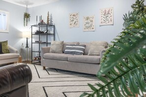 En stue med en sofa, et sofabord, en lampe og en bogreol.