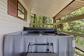 A hot tub on a wooden deck with a view of trees.