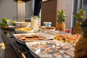 A buffet table with various food items including fruits, dairy products, and snacks.
