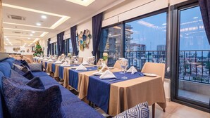 A hotel dining area with tables set for dining, a Christmas tree, and a view of the city through large windows. - Souare Premium Hotel (Conakry)