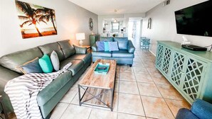 Un salon avec un canapé, une table basse et un téléviseur posé sur un meuble.