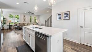 A modern kitchen with a dishwasher, a sink, and a dining area with a table and chairs. - College & Mimosa House in Downtown Auburn, less than 1 mile to Toomer's (Auburn)
