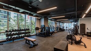 Et fitnessrum med træningsudstyr, en bænk og et vægtstativ.