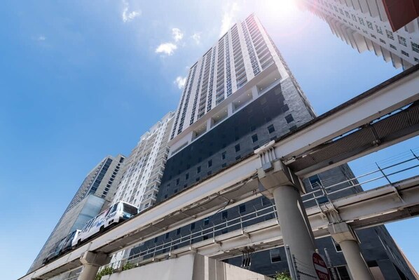 A high-rise building with multiple floors, a pedestrian overpass, and a clear sky.