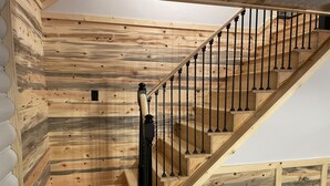A wooden staircase with black balusters and a handrail, leading to an upper floor.